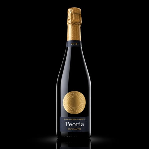 Bottle of Teoria sparkling wine with gold foil cap and label featuring a sun motif on black background